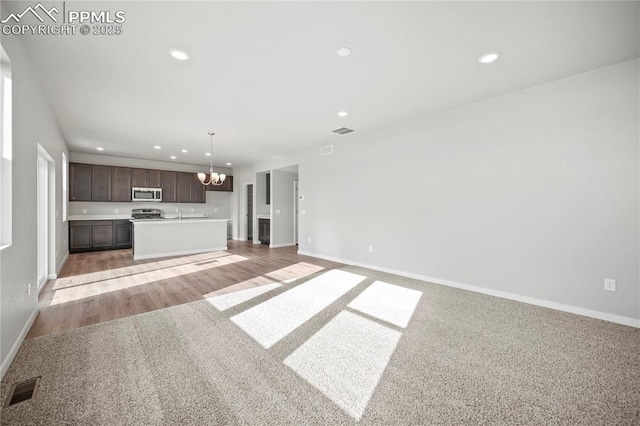 unfurnished living room featuring light carpet and a chandelier