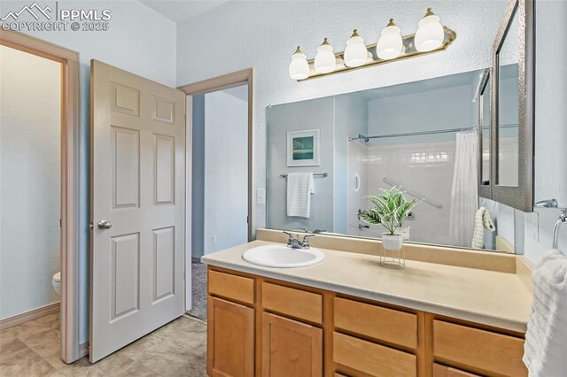 bathroom featuring toilet, vanity, and curtained shower