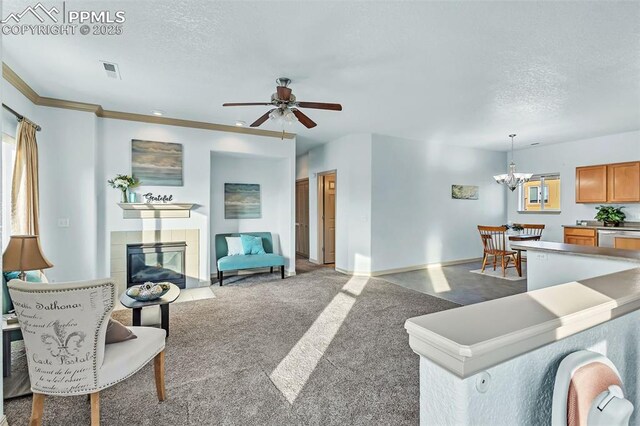 carpeted living room with ceiling fan with notable chandelier, a fireplace, and a textured ceiling