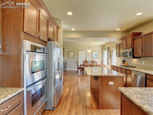 1235 Woodmoor Acres Dr, Monument, CO 80132 - kitchen with decorative light fixtures, light stone countertops, stainless steel appliances, and light hardwood / wood-style flooring