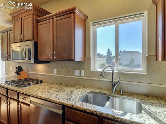 1235 Woodmoor Acres Dr, Monument, CO 80132 - kitchen with tasteful backsplash, light stone counters, sink, and appliances with stainless steel finishes