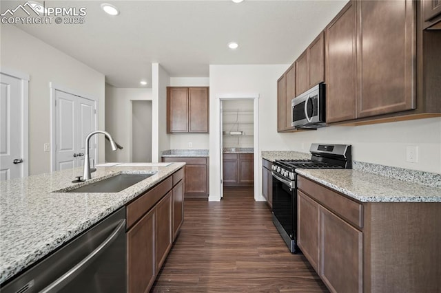 kitchen with dark hardwood / wood-style floors, appliances with stainless steel finishes, light stone counters, and sink