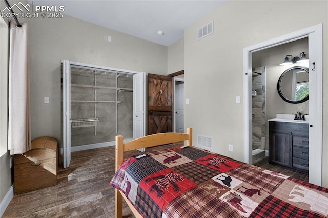 bedroom with connected bathroom and dark wood-type flooring