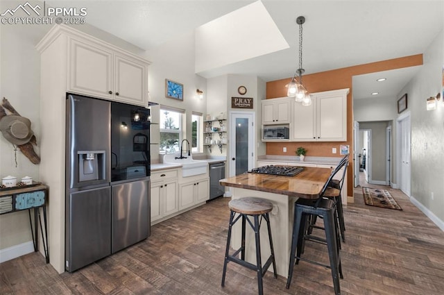 kitchen featuring wooden counters, stainless steel appliances, sink, white cabinets, and a kitchen island