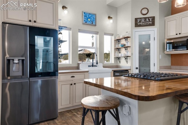 kitchen with wood counters, a breakfast bar, white cabinets, and appliances with stainless steel finishes