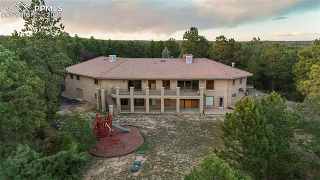 back house at dusk featuring a patio and a balcony