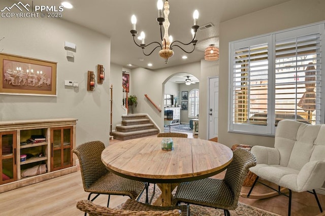 dining space featuring ceiling fan with notable chandelier and light wood-type flooring