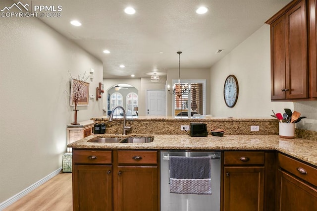 kitchen with dishwasher, sink, light stone counters, light hardwood / wood-style flooring, and pendant lighting