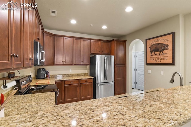 kitchen featuring kitchen peninsula, light stone counters, and appliances with stainless steel finishes