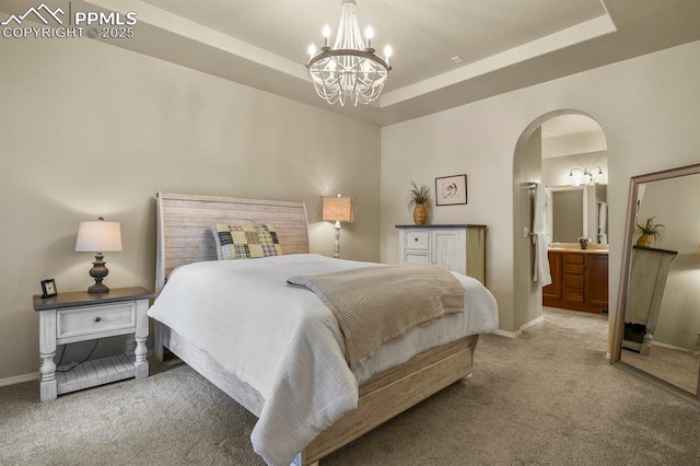 bedroom featuring carpet flooring, ensuite bathroom, a raised ceiling, and a chandelier