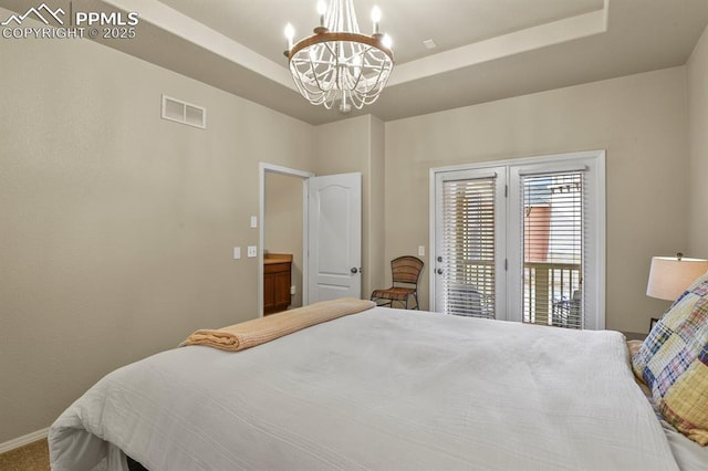 bedroom featuring a raised ceiling, access to outside, and a chandelier