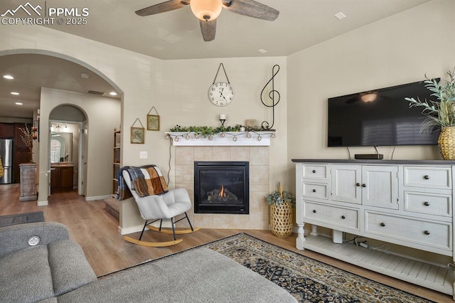 living room featuring a fireplace, light wood-type flooring, and ceiling fan