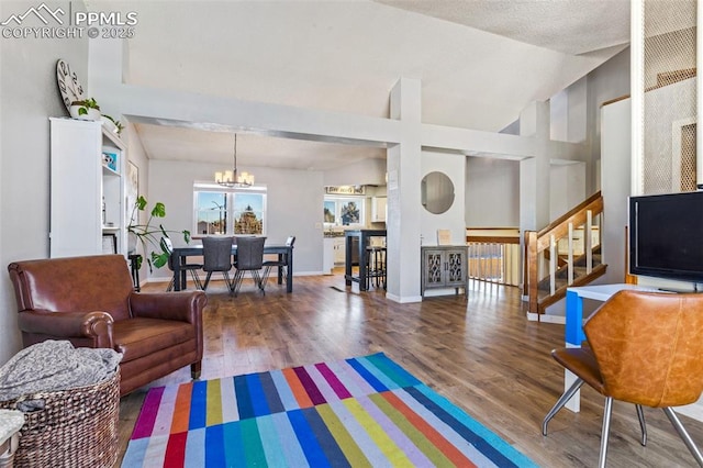 living room with lofted ceiling, a textured ceiling, a chandelier, and hardwood / wood-style flooring