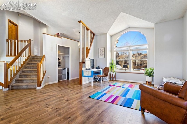 living room featuring vaulted ceiling, a textured ceiling, and hardwood / wood-style floors