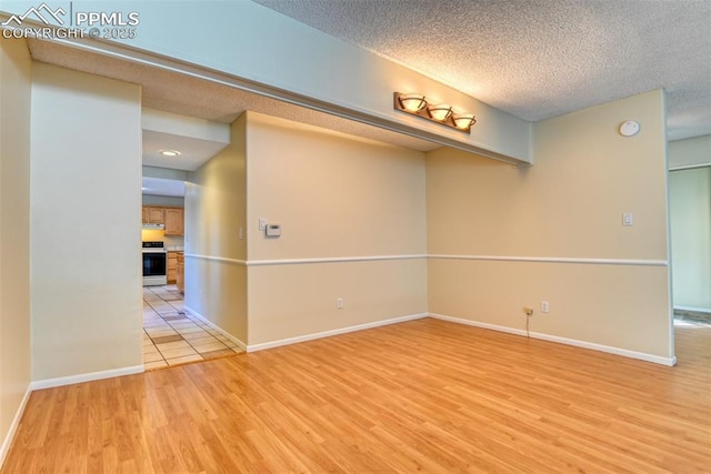 spare room featuring a textured ceiling and light hardwood / wood-style flooring