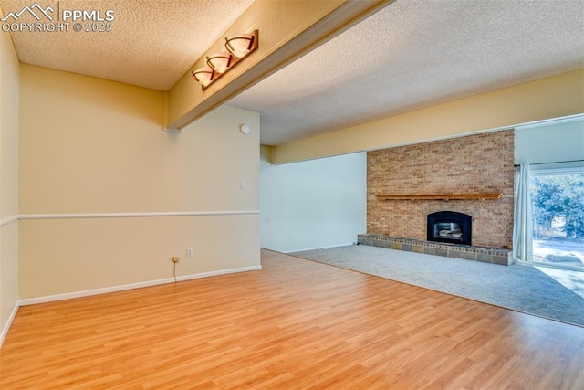 unfurnished living room featuring hardwood / wood-style floors, a textured ceiling, and a brick fireplace