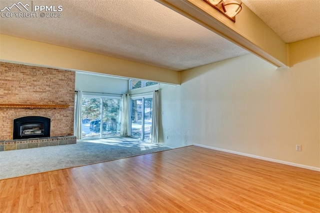 unfurnished living room with a fireplace, a textured ceiling, and hardwood / wood-style flooring