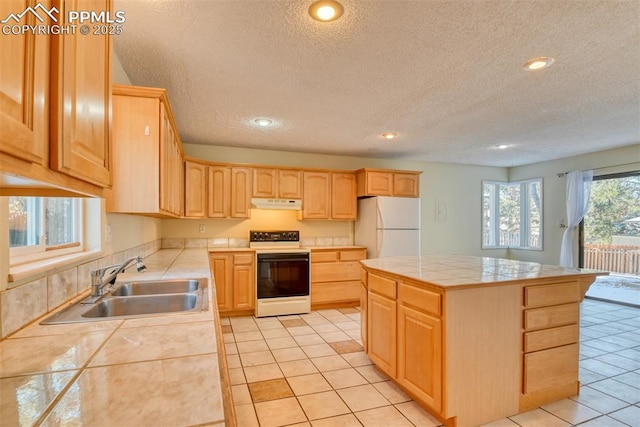 kitchen with light brown cabinets, tile counters, sink, white appliances, and a kitchen island