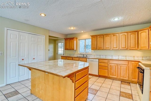 kitchen featuring a center island, white appliances, sink, tile counters, and light tile patterned flooring