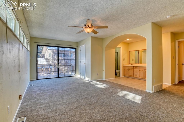 unfurnished living room featuring ceiling fan, light colored carpet, and a textured ceiling