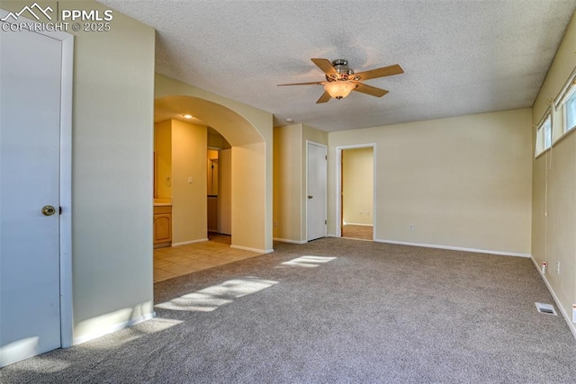 carpeted spare room featuring ceiling fan and a textured ceiling