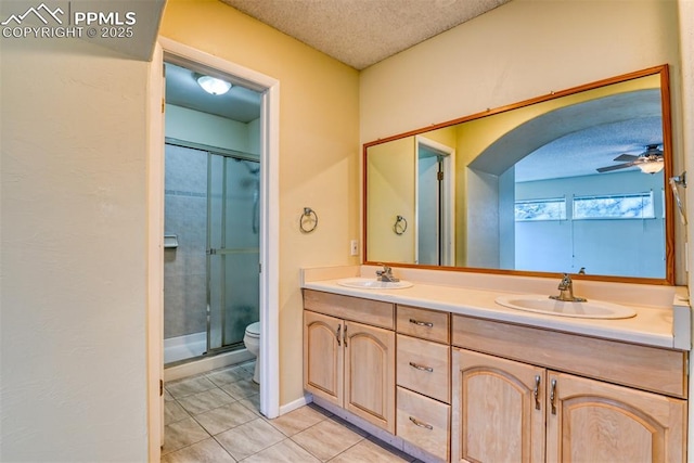 bathroom with vanity, a textured ceiling, ceiling fan, tile patterned flooring, and a shower with shower door