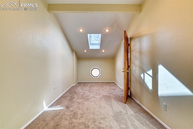 unfurnished room featuring vaulted ceiling with skylight and light colored carpet