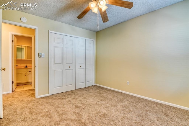 unfurnished bedroom featuring a closet, a textured ceiling, light colored carpet, and ceiling fan