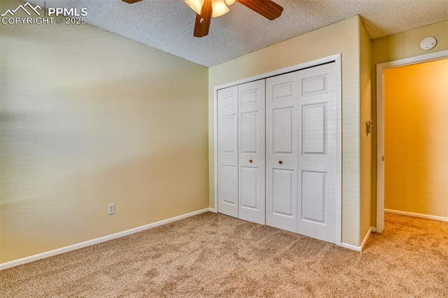 unfurnished bedroom with ceiling fan, a closet, light colored carpet, and a textured ceiling