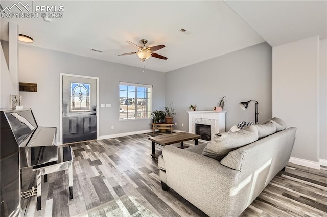 living room with ceiling fan, a premium fireplace, and hardwood / wood-style floors