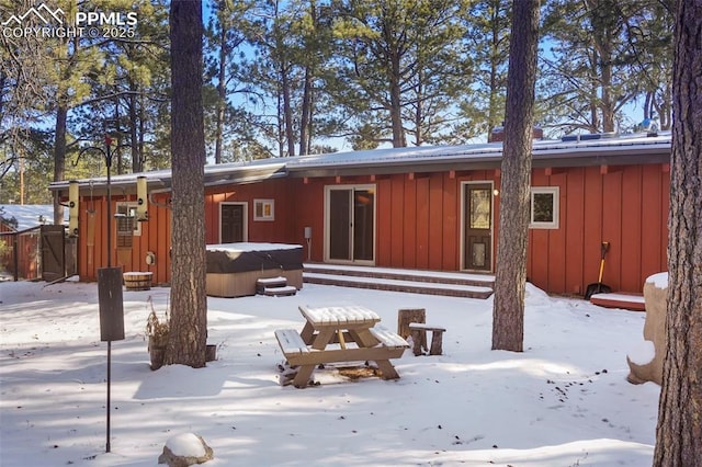 snow covered property with a hot tub