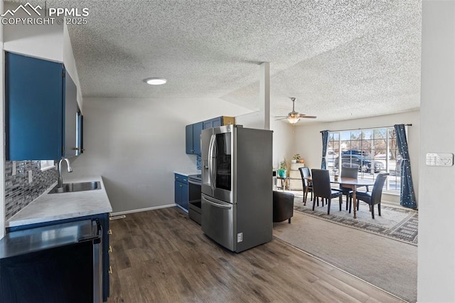 kitchen with blue cabinets, sink, ceiling fan, appliances with stainless steel finishes, and dark hardwood / wood-style flooring