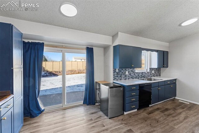 kitchen with stainless steel fridge, black dishwasher, blue cabinetry, and sink