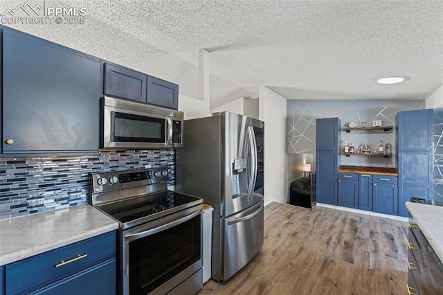 kitchen with dark hardwood / wood-style floors, blue cabinetry, a textured ceiling, tasteful backsplash, and stainless steel appliances