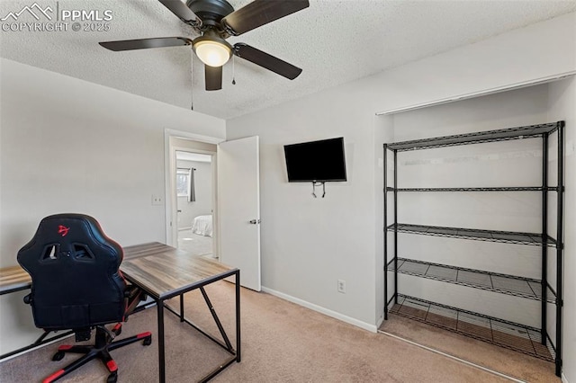 carpeted office with ceiling fan and a textured ceiling