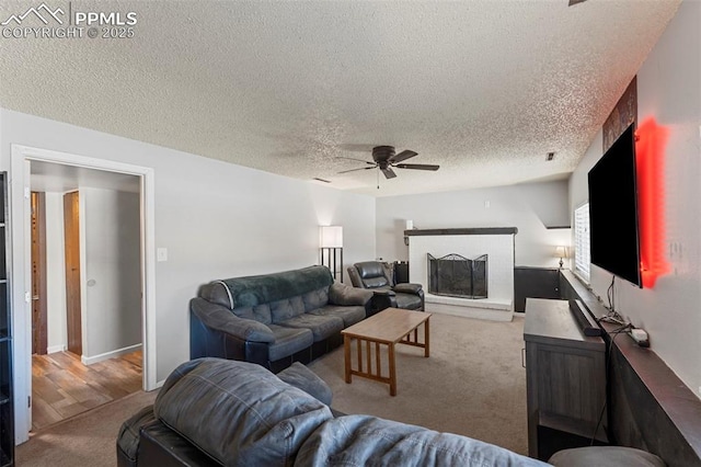 carpeted living room with a fireplace, a textured ceiling, and ceiling fan