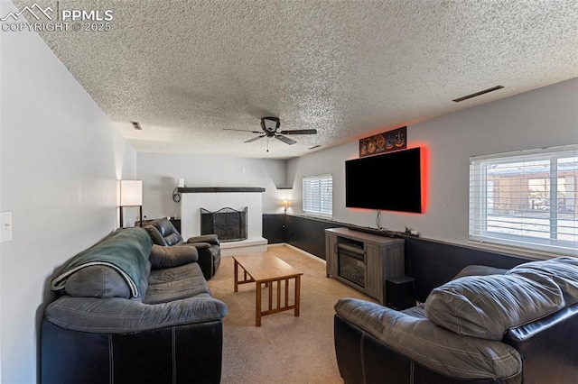 carpeted living room featuring ceiling fan, a textured ceiling, and a brick fireplace