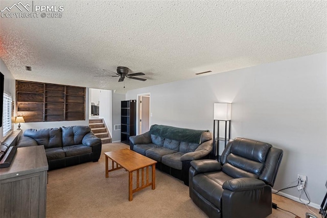 carpeted living room with built in shelves, ceiling fan, and a textured ceiling