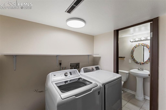 laundry area featuring washer and clothes dryer, light tile patterned flooring, and sink