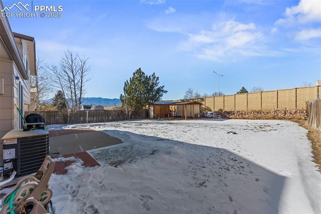 yard layered in snow featuring a mountain view and central AC unit