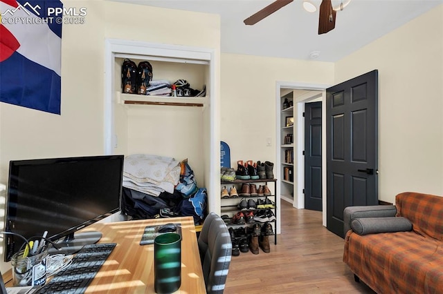 interior space featuring built in shelves, hardwood / wood-style flooring, and ceiling fan