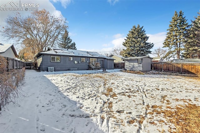 snow covered house with cooling unit and a shed