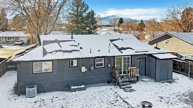 snow covered property with a mountain view and central AC