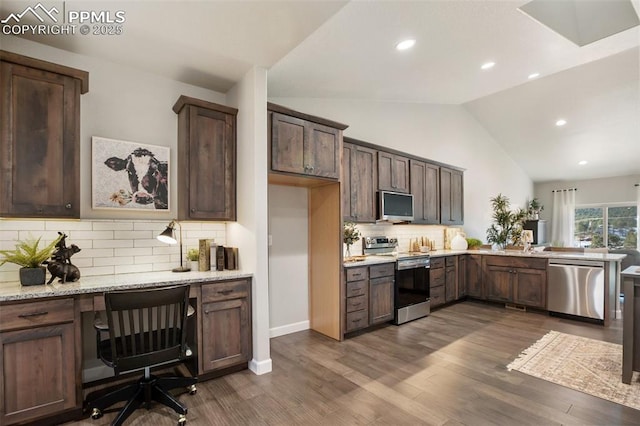 kitchen with lofted ceiling, dark hardwood / wood-style floors, light stone countertops, appliances with stainless steel finishes, and tasteful backsplash