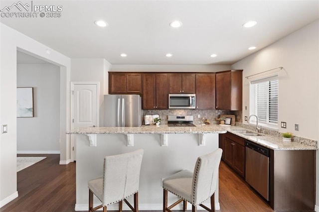 kitchen with appliances with stainless steel finishes, a kitchen island, dark wood-type flooring, and sink