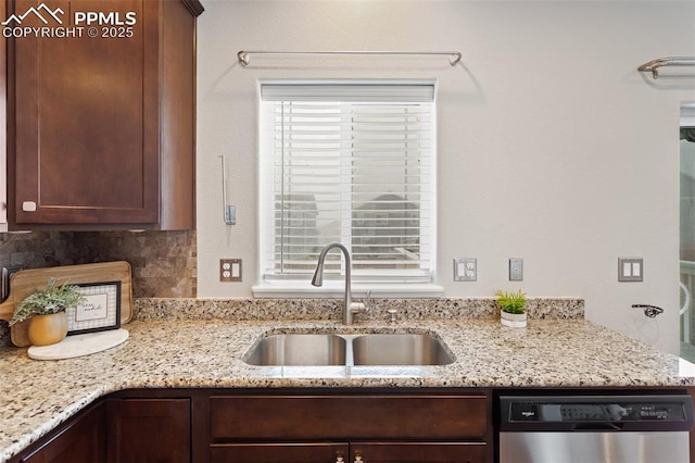 kitchen featuring backsplash, dishwasher, light stone countertops, and sink