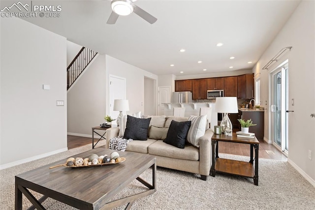 living room featuring light carpet, ceiling fan, and sink