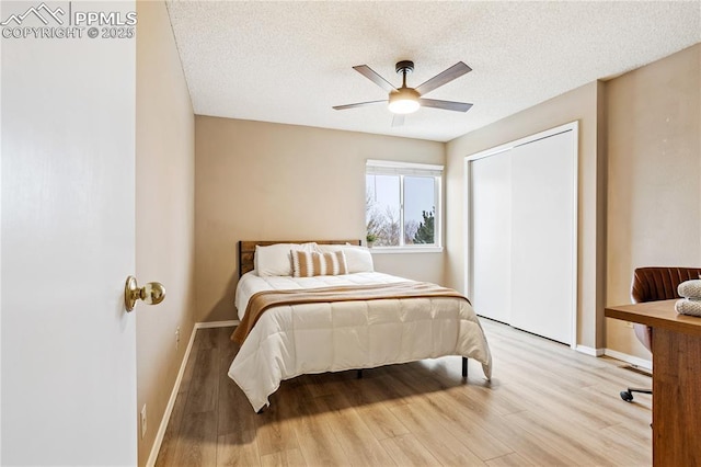 bedroom with ceiling fan, a closet, light hardwood / wood-style floors, and a textured ceiling