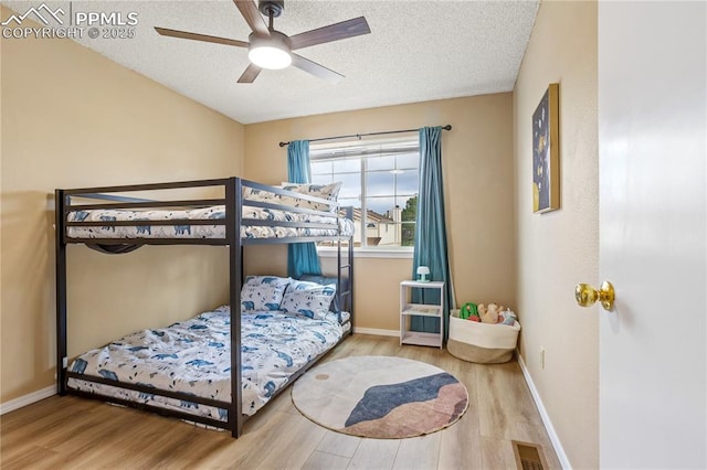 bedroom with hardwood / wood-style flooring, ceiling fan, and a textured ceiling