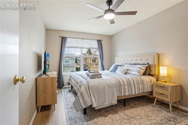 bedroom with a textured ceiling, hardwood / wood-style flooring, and ceiling fan